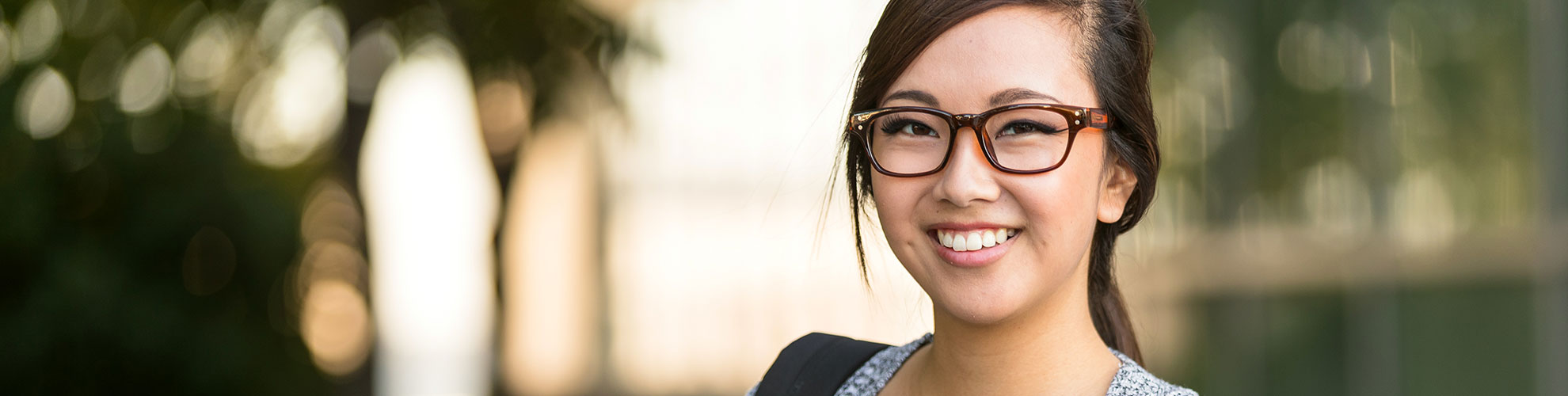 Young woman smiling outdoors wearing glasses