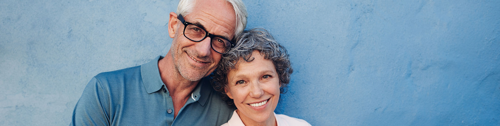 mature couple smiling against blue wall