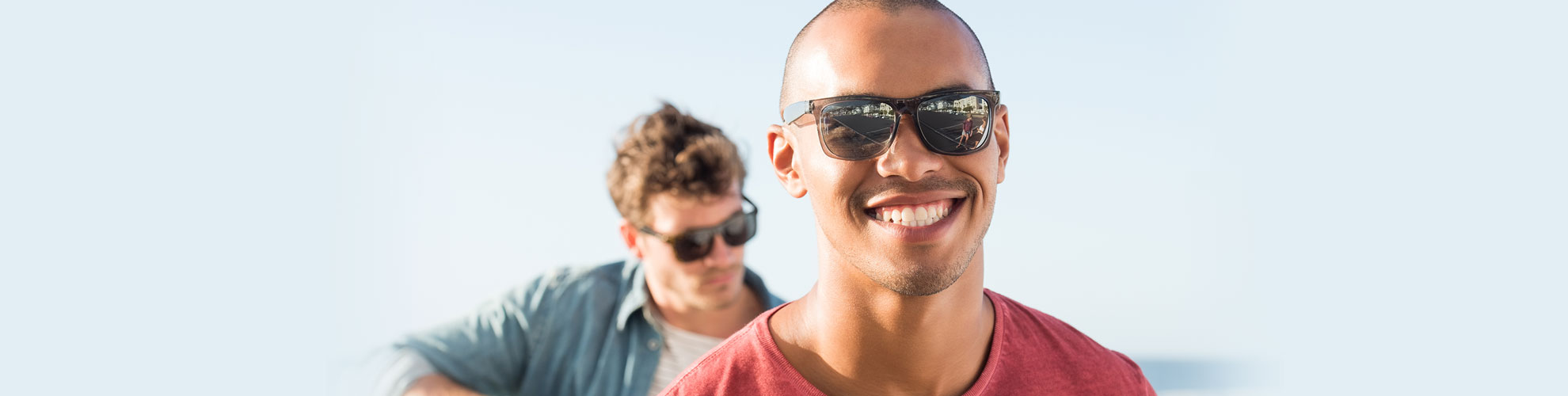 young men outside playing guitar wearing sunglasses smiling 