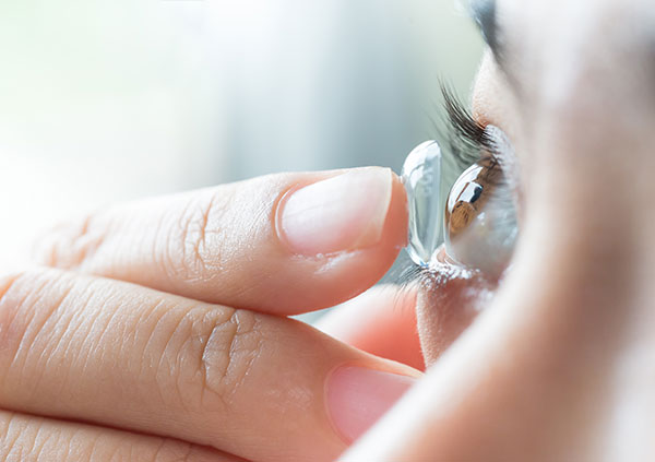 Women inserting a contact lens contact lenses